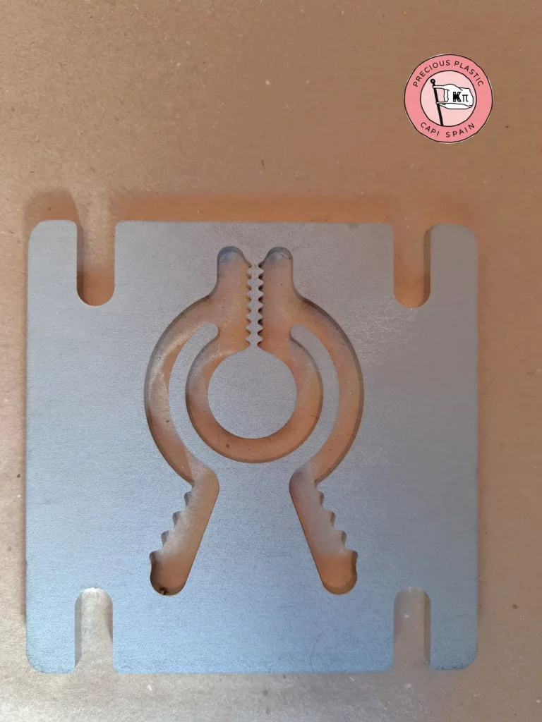 Stainless steel mini injection mould plate with a piranha clip shape, from Precious Plastic Capi Spain's Mini Injection Moulds Series.