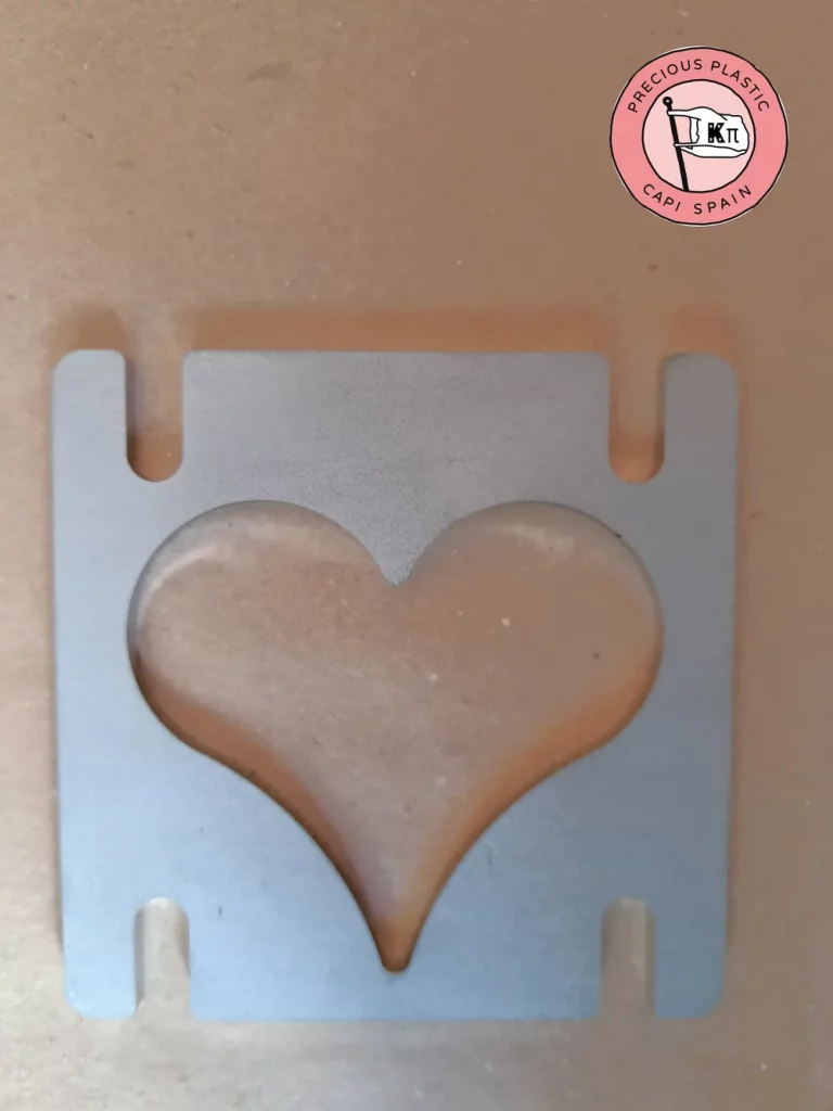 Stainless steel mini injection mould plate with a heart shape, from Precious Plastic Capi Spain's Mini Injection Moulds Series.