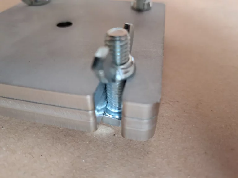 Close-up detail of a stainless steel wing nut and bolt quick-release fastening system on the corner of a modular mini mould.