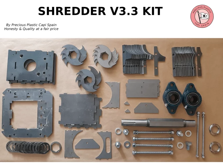Metal components and hardware parts of the Precious Plastic Shredder V3.3 heavy‑duty model, including blades, plates, bearings, and bolts, arranged for assembly — made in Spain.