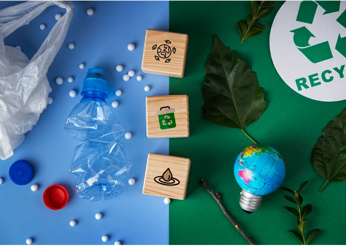 Composición sobre sostenibilidad: botella de plástico reciclada frente a elementos naturales y símbolos de reciclaje - Precious Plastic Capi Spain