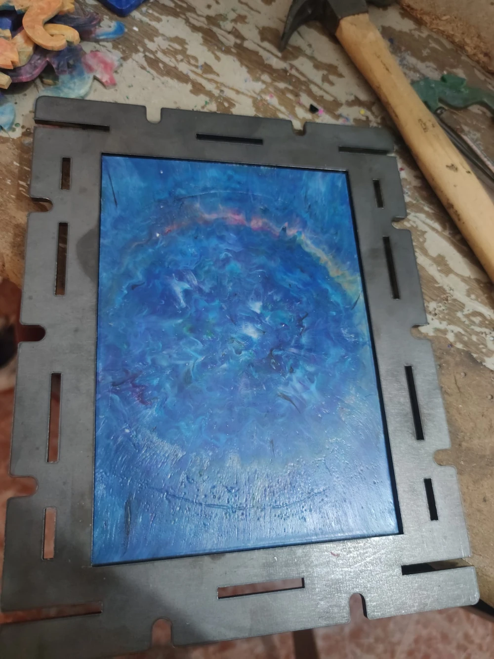 Molde A4 Sheetpress de acero con una lámina de plástico reciclado azul fundida en su interior sobre un banco de trabajo.