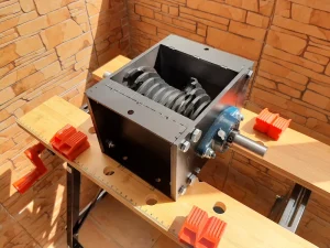 Precious Plastic V2.1 shredder box fully assembled, welded, and painted on a wooden workbench.