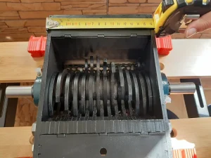 Mesure de la largeur interne de la trémie du bloc assemblé du broyeur Precious Plastic V2.1 à l'aide d'un mètre ruban.