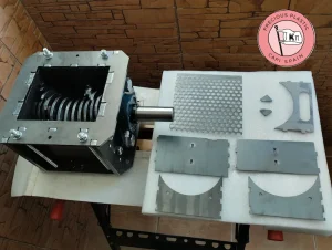 Assembled V3.3 shredder box next to the disassembled components of the perforated screen and sieve steel plates.
