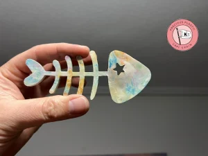Mano sosteniendo una figura de espina de pescado hecha de plástico reciclado veteado, fabricada con un molde de inyección personalizado.